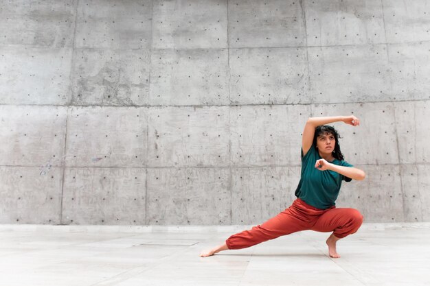 Giovane donna latina che esegue una danza davanti a un muro di cemento