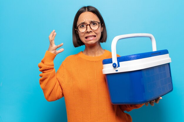 Giovane donna latina che grida con le mani in alto, sentendosi furiosa, frustrata, stressata e sconvolta