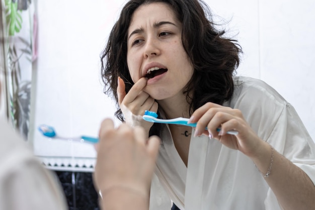 Giovane donna latina che guarda lo specchio mentre soffre di mal di denti