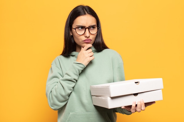 Giovane donna latina che pensa, si sente dubbiosa e confusa, con diverse opzioni, chiedendosi quale decisione prendere