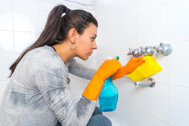 Giovane donna latina che pulisce le piastrelle del bagno