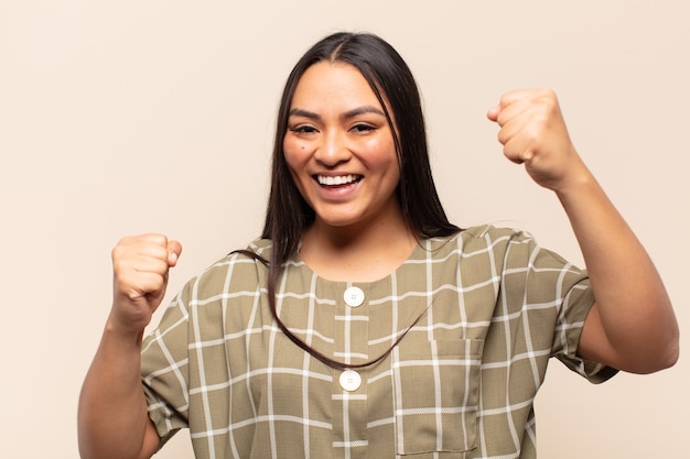 Giovane donna latina che si sente felice, positiva e di successo, celebra la vittoria, i risultati o la buona fortuna