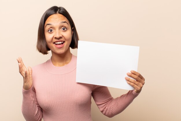 Giovane donna latina che si sente felice, sorpresa e allegra, sorridente con atteggiamento positivo, realizzando una soluzione o un'idea