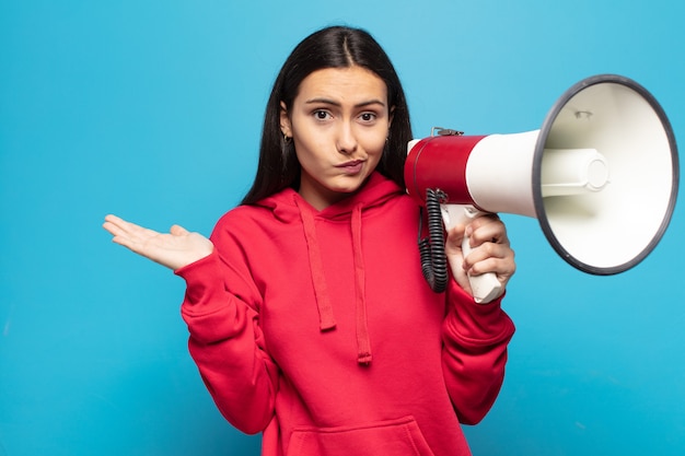 Giovane donna latina che si sente perplessa e confusa, dubbiosa, ponderata o scegliendo diverse opzioni con un'espressione divertente