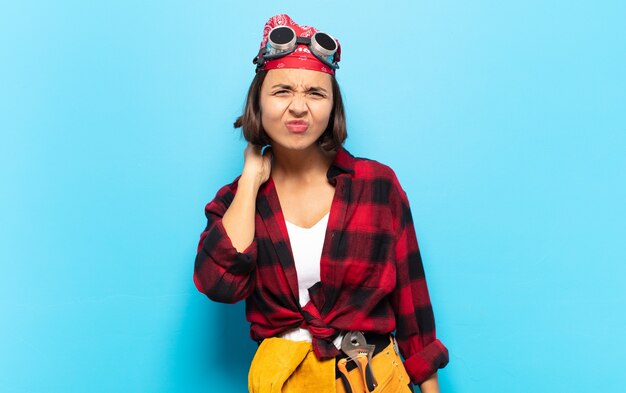 Giovane donna latina che si sente stressata, frustrata e stanca, strofinando il collo doloroso, con uno sguardo preoccupato e turbato