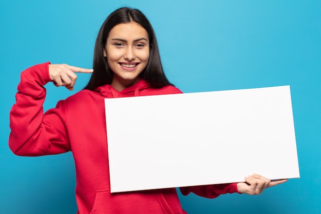 Giovane donna latina che sorride fiduciosamente indicando il proprio ampio sorriso, positivo