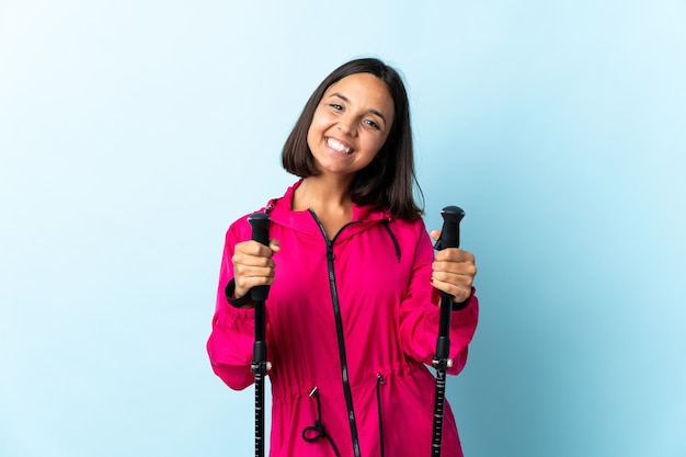 Giovane donna latina con zaino e bastoncini da trekking