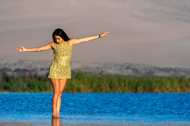 Giovane donna latina in posa sull'acqua a braccia aperte in abito all'apertox9