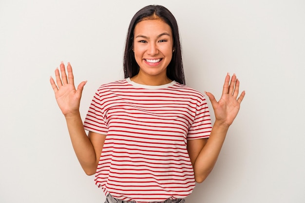 Giovane donna latina isolata su sfondo bianco che riceve una piacevole sorpresa eccitata e alzando le mani