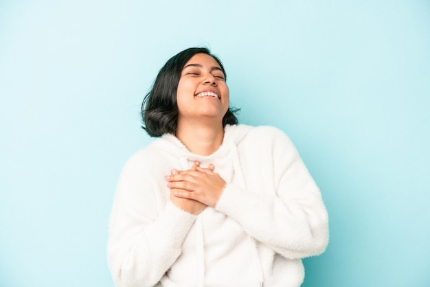 Giovane donna latina isolata su sfondo blu che ride tenendo le mani sul cuore, concetto di felicità.