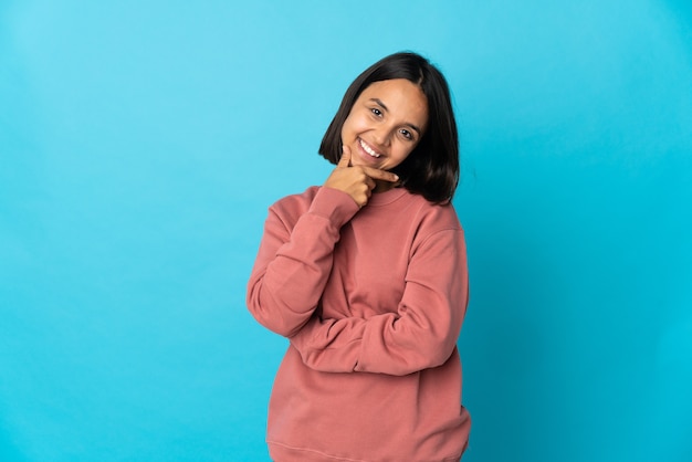 Giovane donna latina isolata su sfondo blu felice e sorridente