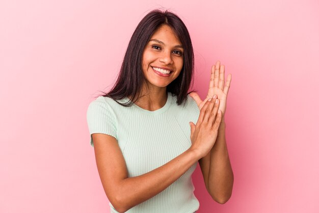 Giovane donna latina isolata su sfondo rosa che si sente energica e a suo agio, sfregandosi le mani fiduciose.