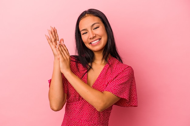 Giovane donna latina isolata su sfondo rosa che si sente energica e a suo agio, sfregandosi le mani fiduciose.