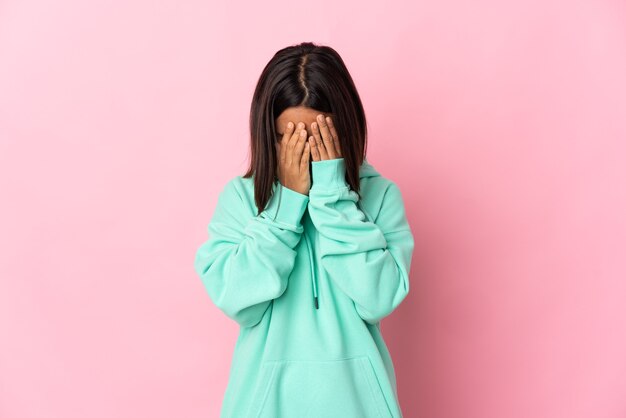 Giovane donna latina isolata su sfondo rosa con espressione stanca e malata