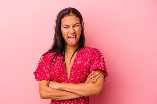 Giovane donna latina isolata su sfondo rosa divertente e amichevole con la lingua fuori.