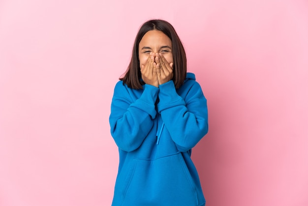 Giovane donna latina isolata su sfondo rosa felice e sorridente che copre la bocca con le mani