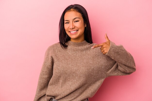 Giovane donna latina isolata su sfondo rosa persona che indica a mano uno spazio per la copia di una camicia, orgogliosa e fiduciosa