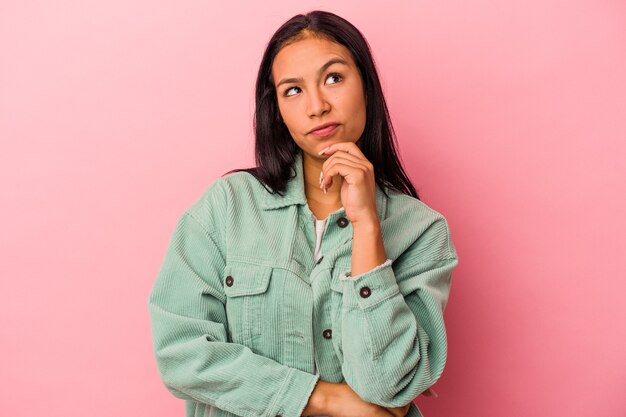 Giovane donna latina isolata su sfondo rosa rilassata pensando a qualcosa guardando uno spazio di copia.