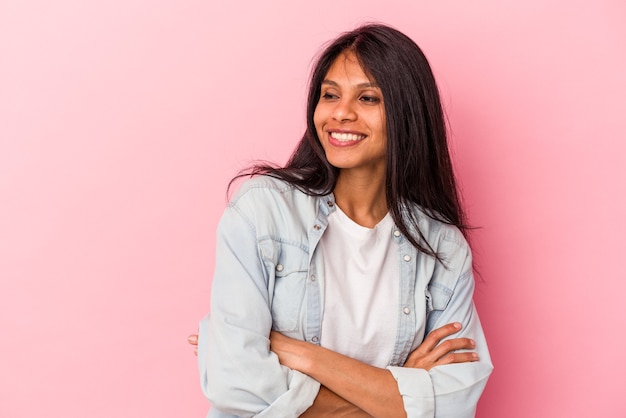 Giovane donna latina isolata su sfondo rosa sorridente fiducioso con le braccia incrociate.