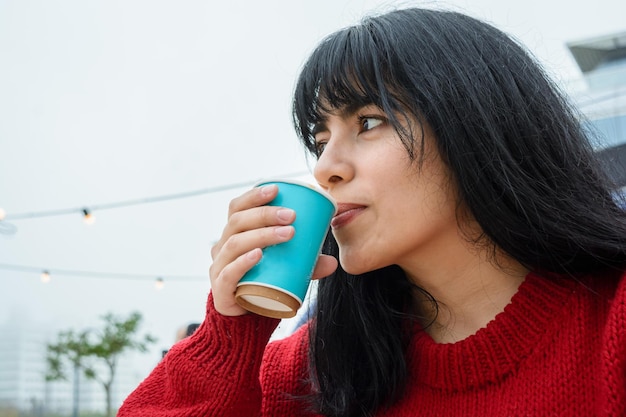 giovane donna latina seduta all'aperto gustando una tazza di caffè