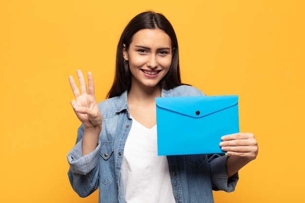 Giovane donna latina sorridente e dall'aspetto amichevole, mostrando il numero tre o il terzo con la mano in avanti, conto alla rovescia