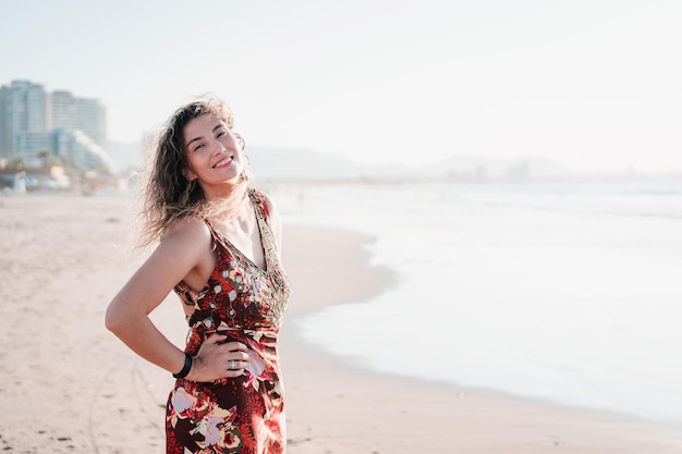 Giovane donna latina sorridente felice sulla spiaggia guardando il ritratto della fotocamera a La Serena