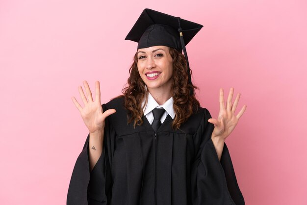 Giovane donna laureata isolata su sfondo rosa che conta dieci con le dita