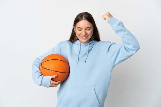 Giovane donna lituana che gioca a basket isolato sul muro bianco facendo un forte gesto