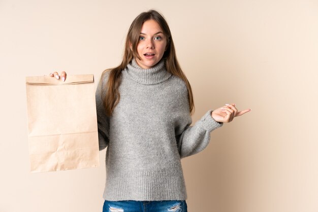 Giovane donna lituana che tiene un sacchetto della spesa della drogheria sorpresa e che indica il dito a lato
