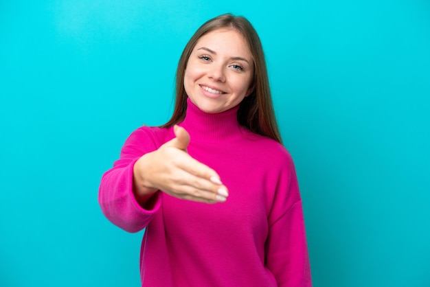 Giovane donna lituana isolata su sfondo blu che stringe la mano per aver chiuso un buon affare