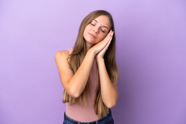 Giovane donna lituana isolata su sfondo viola che fa il gesto del sonno in un'espressione adorabile