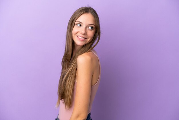 Giovane donna lituana isolata su sfondo viola che guarda di lato e sorridente