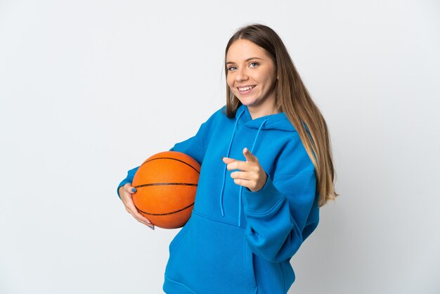 Giovane donna lituana isolata sul muro bianco, giocando a basket e indicando la parte anteriore