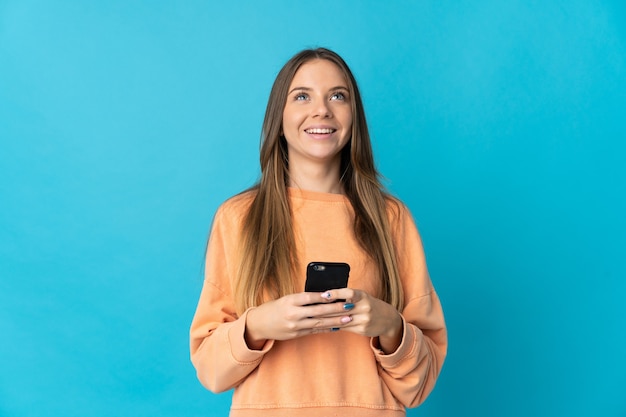 Giovane donna lituana isolata utilizzando il telefono cellulare e alzando lo sguardo