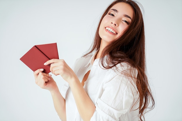 Giovane donna lunga asiatica sorridente felice dei capelli con due passaporti su fondo bianco isolato