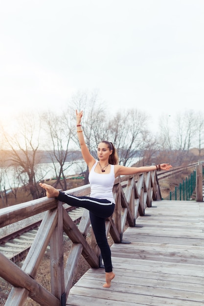 Giovane donna magra che si allena nella natura Facendo esercizi di pilates di yoga all'aria aperta