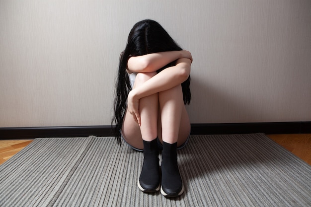 Giovane donna maltrattata che si siede vicino alla parete