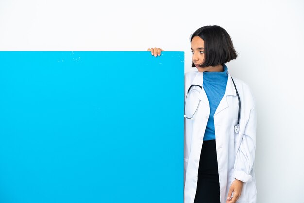 Giovane donna medico di razza mista con un grande cartello isolato guardando al lato