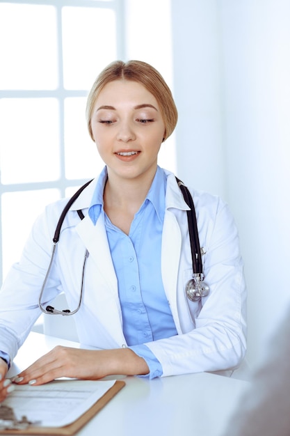 Giovane donna medico e paziente alla visita medica presso l'ufficio dell'ospedale. La camicetta blu del terapeuta sembra buona. Concetto di medicina e assistenza sanitaria.