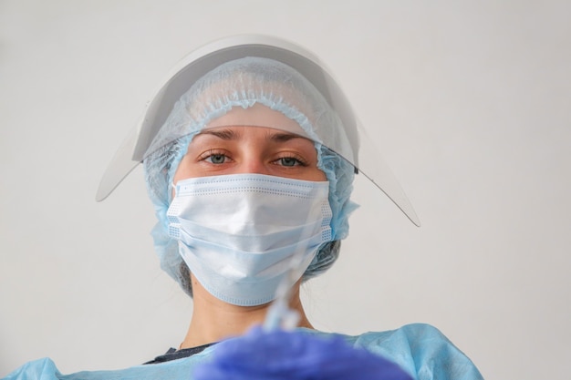 giovane donna medico in una tuta protettiva e maschera con una siringa