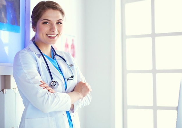 Giovane donna medico in uniforme bianca in piedi nell'ufficio delle cliniche