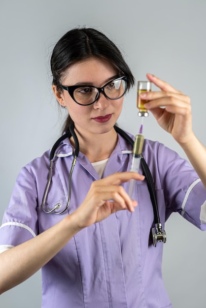 Giovane donna medico o infermiere in uniforme medica bianca e guanti con siringa in mano su sfondo isolato concetto di medicina ritratto di una donna paura degli aghi