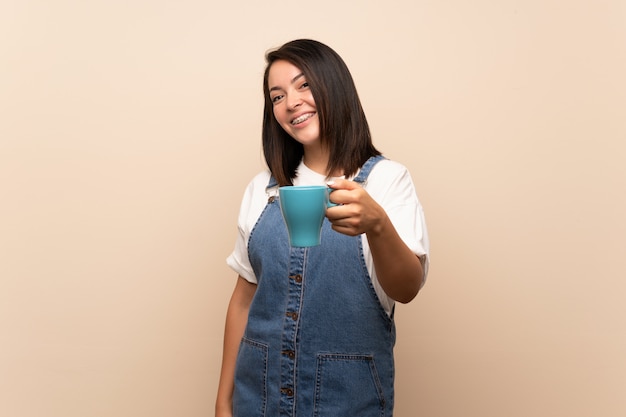 Giovane donna messicana che tiene tazza di caffè calda