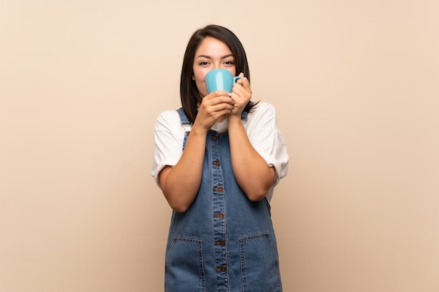 Giovane donna messicana sopra isolato tenendo caldo tazza di caffè