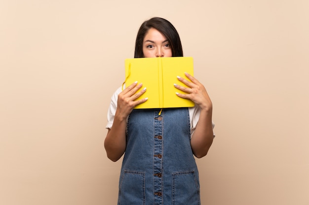 Giovane donna messicana su sfondo isolato holding e leggendo un libro