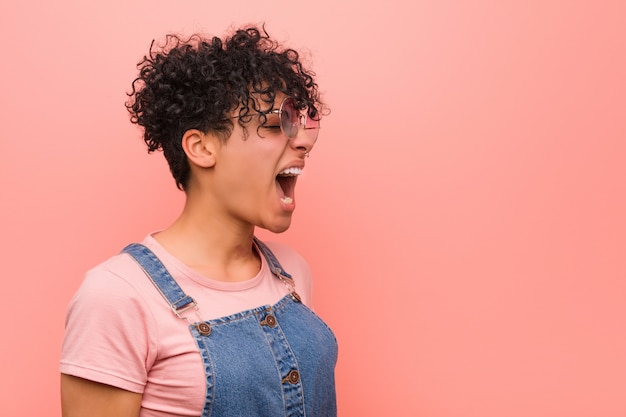 Giovane donna mista dell'adolescente dell'afroamericano che grida verso uno spazio della copia