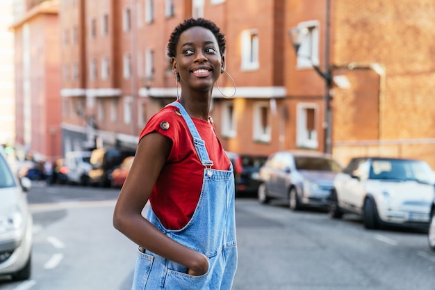 Giovane donna modello africano nero che attraversa la strada di una città molto sorridente