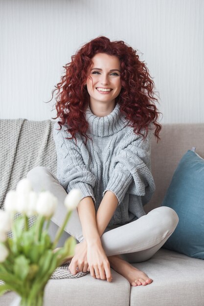 Giovane donna molto attraente in casa. Ritratto di donna dai capelli ricci. Bella donna dai capelli rossi a casa.