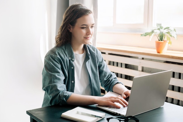 Giovane donna multitasking con un computer portatile in un ambiente d'ufficio moderno e studentessa focalizzata su wo