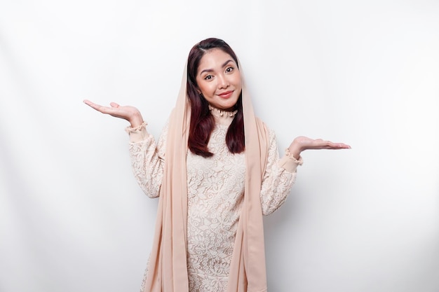 Giovane donna musulmana asiatica che sorride mentre indica per copiare lo spazio accanto a lei